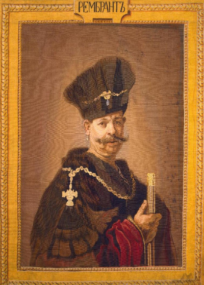 Tkanina zabytkowa tzw. tapiseria ze „Szlachcicem polskim” Rembrandta. Przedstawia mężczyznę z wąsem, ubranego w strój historyczny, w tym czapkę. Mężczyzna ma zarzucony na ramiona płaszcz, lub delię, a jej kołnierz ozdobiony jest złotym łańcuchem z krzyżem. Podobnie czapka ozdobiona jest łańcuchem. Szlachcic trzyma w prawej dłoni złoty, wąski przedmiot.