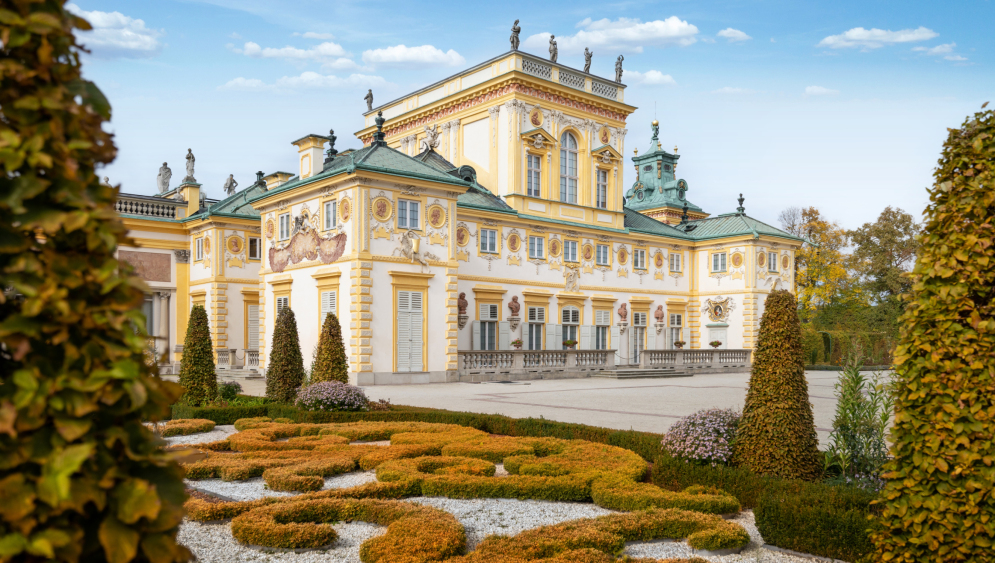 Widok na pałac w Wilanowie od strony ogrodów. Na pierwszym planie złote rabaty, krzewy i drzewa. 